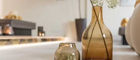 Zwei braune Glasvasen mit weißen Blumen auf einem Tisch in einem Wohnzimmer