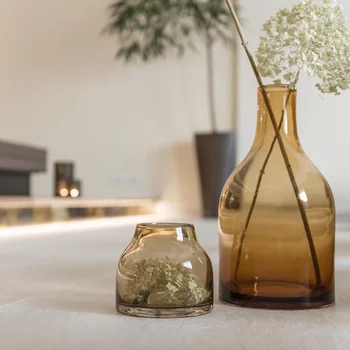 Zwei braune Glasvasen mit weißen Blumen auf einem Tisch in einem Wohnzimmer