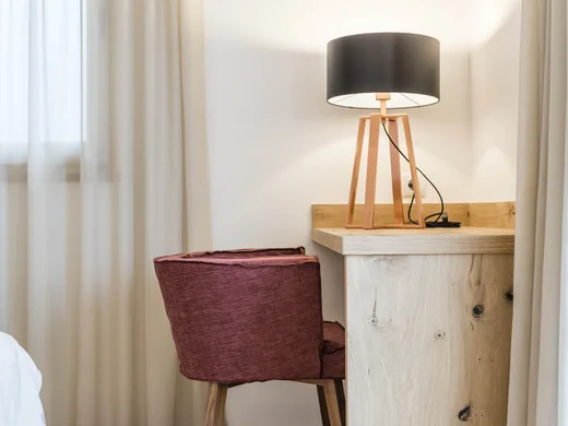 Room Rotes Stuhl vor Holztisch mit schwarzer Lampenschirmlampe in einem hellen Raum
