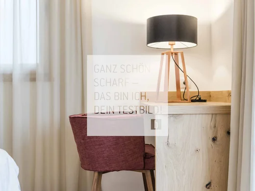 Room Rotes Stuhl vor Holztisch mit schwarzer Lampenschirmlampe in einem hellen Raum