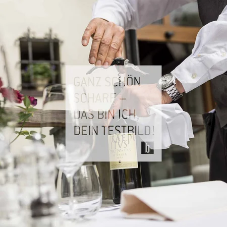 General Kellner öffnet Weinflasche mit Korkenzieher am gedeckten Tisch