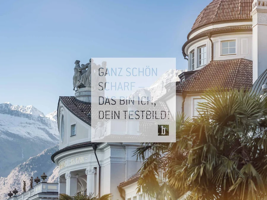 Historisches Gebäude und schneebedeckte Berge im Hintergrund bei klarem Himmel