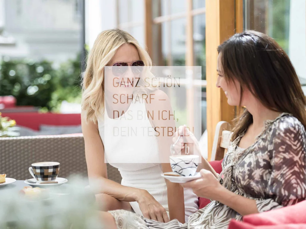 Zwei Frauen trinken Kaffee draußen in einem Café und unterhalten sich
