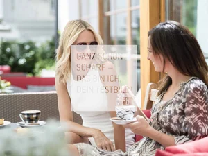 Zwei Frauen trinken Kaffee draußen in einem Café und unterhalten sich