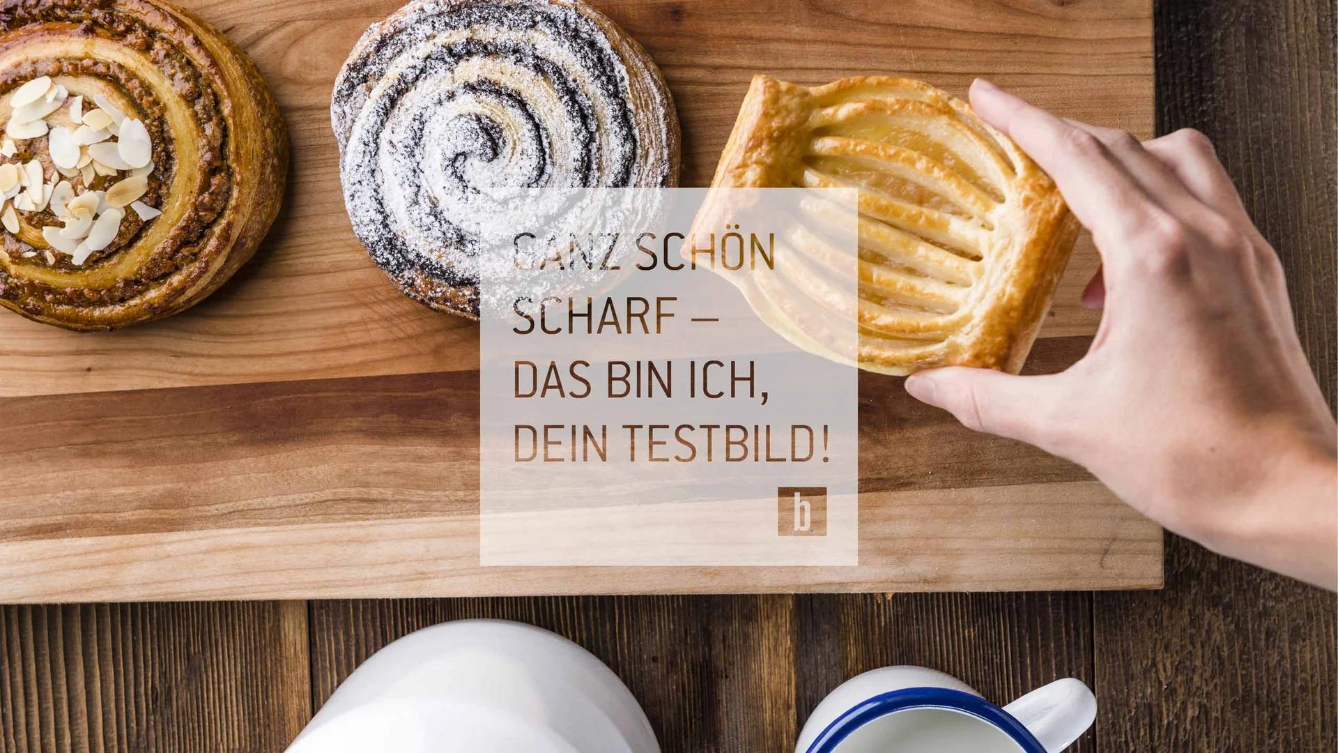 Hand nimmt Gebäckstück von Holzbrett mit drei verschiedenen Süßgebäcken