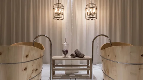 Zwei Holzwannen mit Wasserhähnen und zwei hängende Metalllampen vor Vorhang