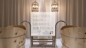 Two wooden tubs with faucets and two hanging metal lights in front of curtain