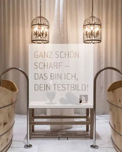 Zwei Holzwannen mit Wasserhähnen und zwei hängende Metalllampen vor Vorhang