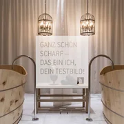 Zwei Holzwannen mit Wasserhähnen und zwei hängende Metalllampen vor Vorhang