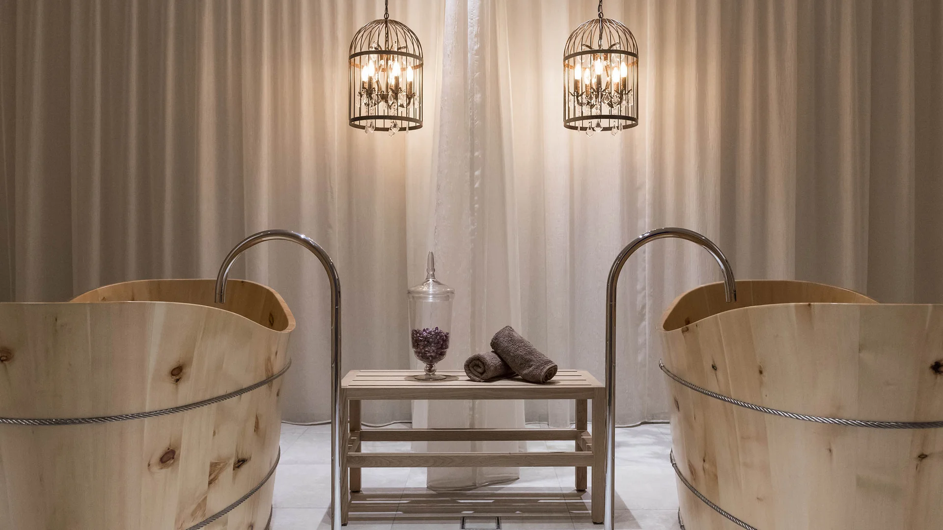 Zwei Holzwannen mit Wasserhähnen und zwei hängende Metalllampen vor Vorhang