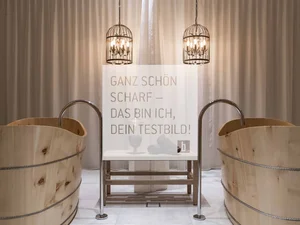 Zwei Holzwannen mit Wasserhähnen und zwei hängende Metalllampen vor Vorhang