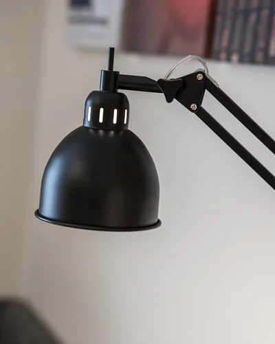Schwarze verstellbare Schreibtischlampe vor unscharfem Hintergrund