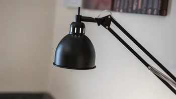 Schwarze verstellbare Schreibtischlampe vor unscharfem Hintergrund