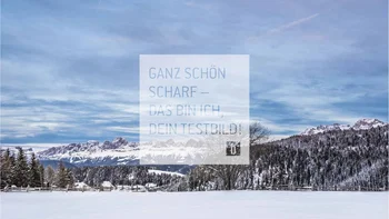 Snow-covered landscape with mountains, trees, and blue sky
