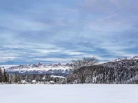 Schneebedeckte Landschaft mit Bergen, Bäumen und blauem Himmel
