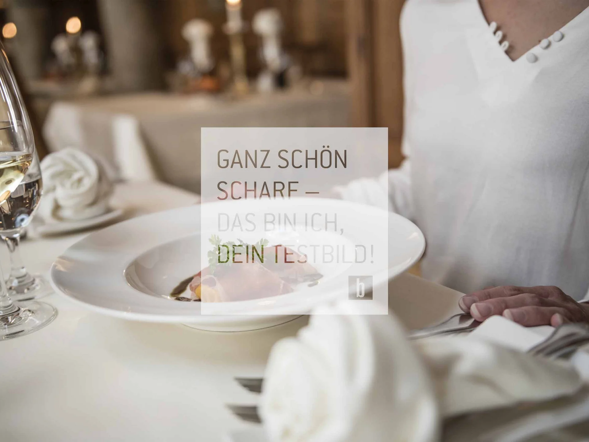 Person sitzt am gedeckten Tisch mit Teller und Weinglas im Restaurant