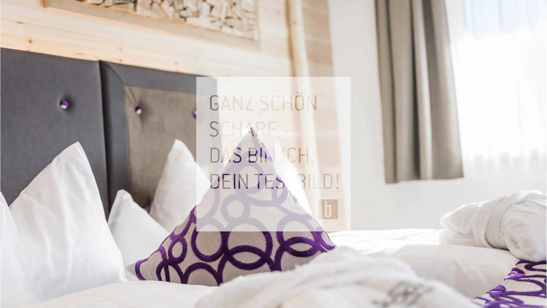 Bequemes Bett mit weißen Kissen und lila gemustertem Kissen