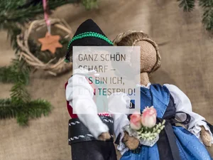 Winter Handgemachte Stoffpuppen in traditioneller Tracht mit Tannenzweigen im Hintergrund