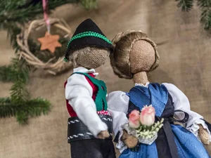Handgemachte Stoffpuppen in traditioneller Tracht mit Tannenzweigen im Hintergrund