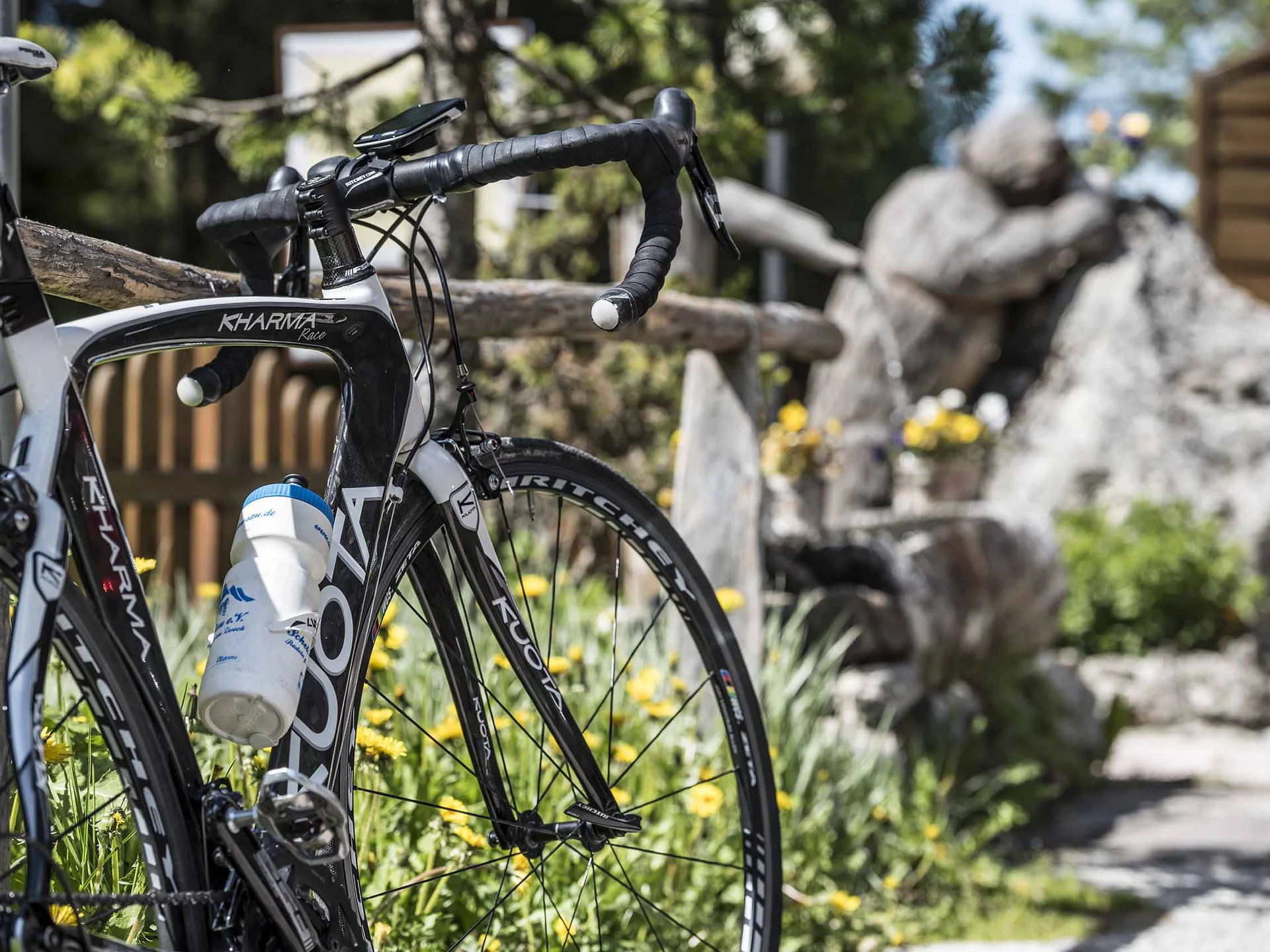Beispielaufbau einer Unterseite Schwarz-weißes Rennrad mit Trinkflasche vor Garten mit Felsen und Blumen