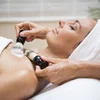 Frau erhält Massage mit Bürsten im Spa, entspannt mit Handtuch am Kopf