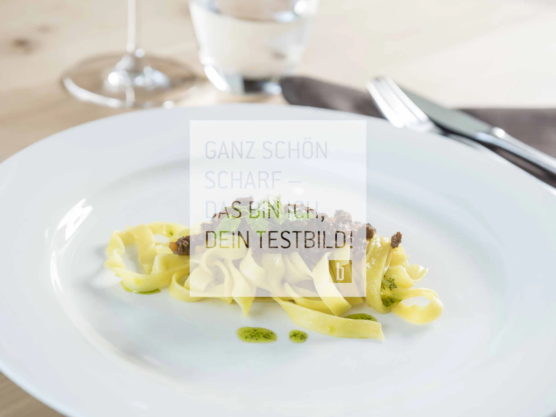 Teller mit kleinen Portion Tagliatelle und Fleischsoße garniert mit Kräutern
