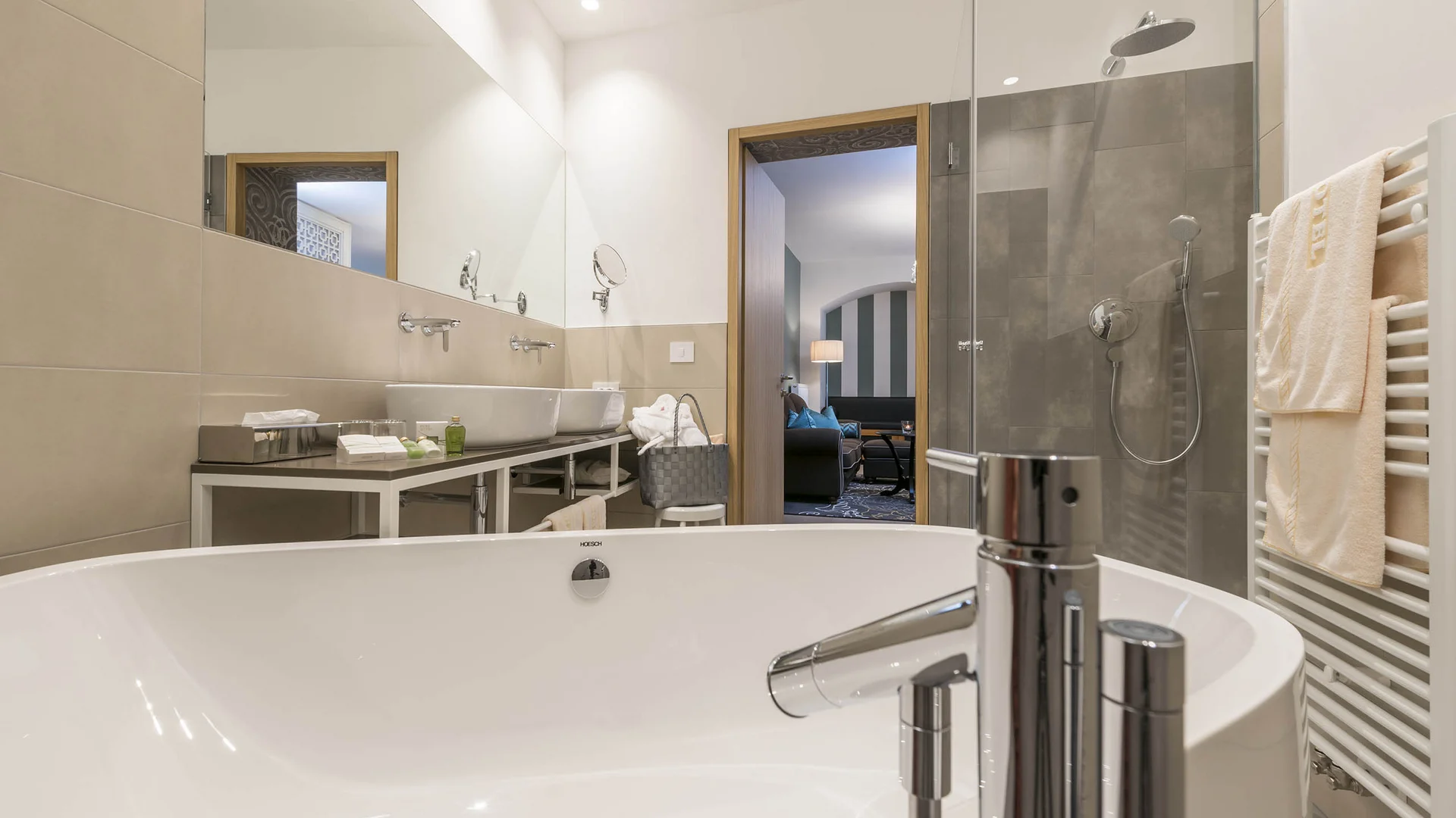 Moderner Badezimmerbereich mit Badewanne, Dusche und Handtüchern