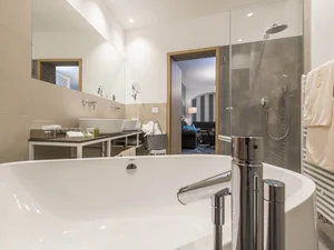 Moderner Badezimmerbereich mit Badewanne, Dusche und Handtüchern