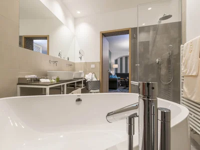 Moderner Badezimmerbereich mit Badewanne, Dusche und Handtüchern
