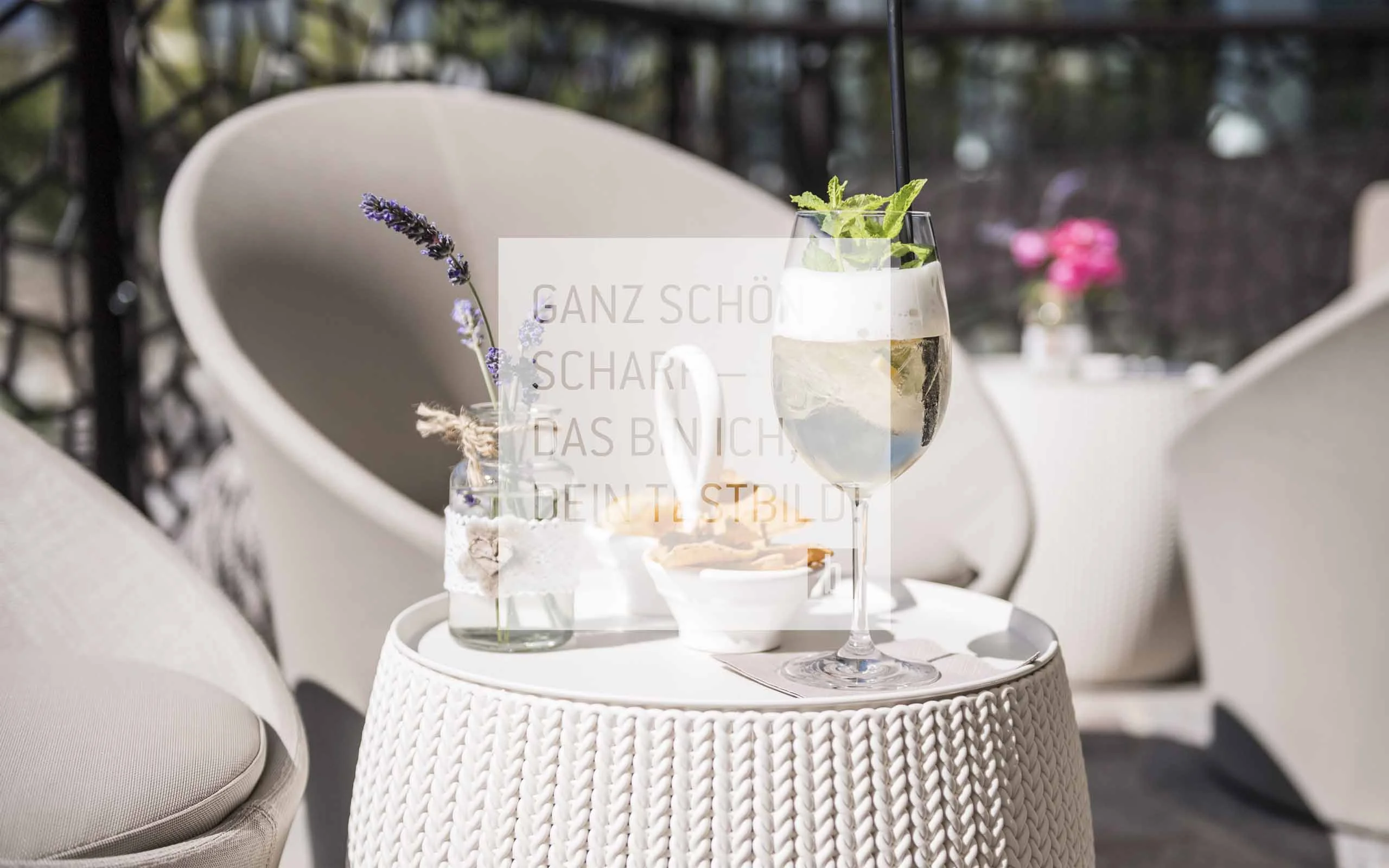 Weißer Beistelltisch mit Cocktail, Snack und dekorativer Vase auf Terrasse
