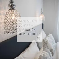 Room Moderne Kristallwandleuchte über einem gemütlichen Schlafzimmer mit Kissen