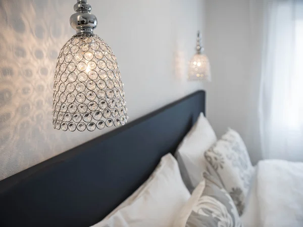 Moderne Kristallwandleuchte über einem gemütlichen Schlafzimmer mit Kissen